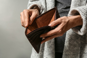 Poor woman showing her empty purse on grey background - obrazy, fototapety, plakaty