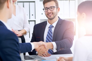 Business handshake at meeting or negotiation in the office. Partners are satisfied because signing contract or financial papers