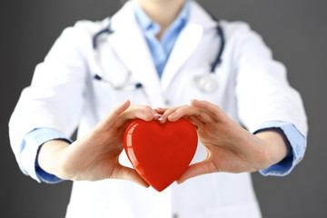 Female doctor with stethoscope holding heart in her arms. Healthcare and cardiology concept  in...