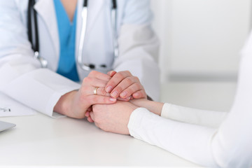 Medicine doctor hand reassuring her female patient closeup. Medicine, comforting  and trusting concept in health care