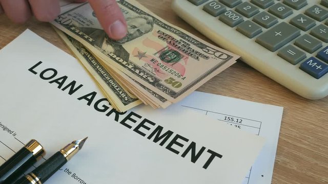 Loan agreement form. Man putting money on an office desk.