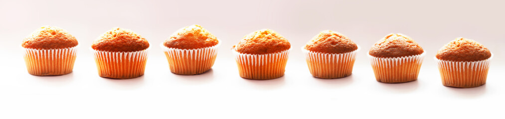 Freshly baked muffins. Seven muffins in wax liner on light background. Small biscuit tasty cupcakes, delicious
