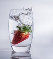 Erdbeere fällt in das Glas mit Wasser