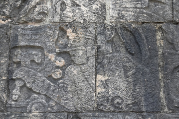 Mayan ball player sculpted on bas relief on the court wall. Detail on Chichen Itza stadium carved on stone. Players had feathered helmets and leather padding for protection. The winner was beheaded. 