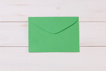 Top View of a invitation or Letter with a Green Envelope. Message or Ticket on Wooden White Desk or Table. Writing a note. Pen, Pencil, a Blank Notebook. Picture. Copy space for text or Image.