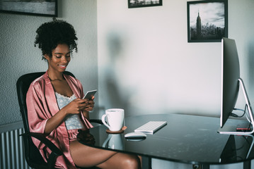 black woman at home working with computer, smartphone and coffee in the morning