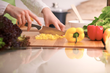 Close Up of human hands cooking vegetable salad in kitchen on the glass table with reflection. Healthy meal, and vegetarian food concept