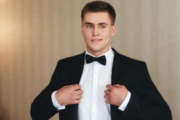 A man dresses a classic black suit and a bow tie © Mironifamily