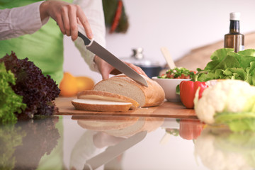 Closeup of human hands cooking in kitchen on the glass table with reflection Housewife slicing bread
