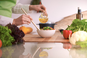 Close Up of human hands cooking vegetable salad in kitchen on the glass table with reflection. Healthy meal, and vegetarian food concept