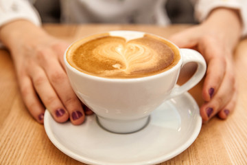 cup cappuccino with foam in the form of a heart and hands