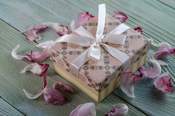 Gift in a box with a bow, petals of a tulip