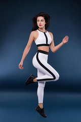 Obraz premium The more you dream, the farther you get. Good-looking gorgeous young lady doing sport in the dark studio in order to keep herself in good shape.