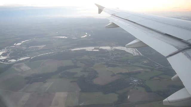View from the airplane window to the vicinities of Paris with a wing of an Airbus plane starting the landing in Paris, airport Charles de Gaulle