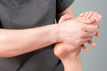 Massage of legs in beauty salon, close view. A woman having a sports foot massage at the spa. A male masseur hand does a female massage. Professional masseur, foot massage.