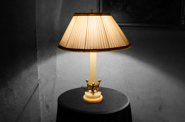 Lamp on a night table next to a bed.