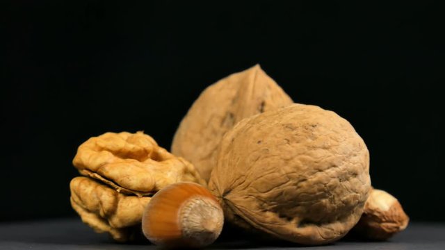 Walnuts end hazelnut nuts in rotation on black background