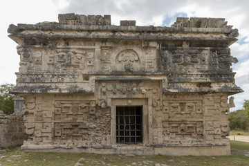 Fototapeta na wymiar The magician's temple at Mayan ruins Chichen Itza. Impressive Stone building with carved details on every side. The Stone masks on the top floor still show ears, nose and teeth. 
