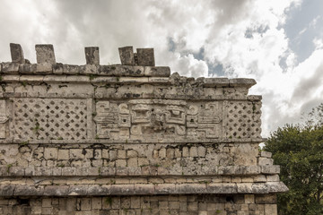 The magician's temple at Mayan ruins Chichen Itza. Impressive Stone building with carved details on every side. The Stone masks on the top floor still show ears, nose and teeth. 