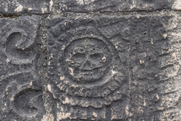 Skull in flower on Mayan wall. detail on bas relief on the ball game court restored in Chichen Itza Mexico. It shows death as part of the cycle of life.