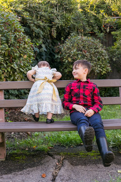 boy and baby sister on park bench