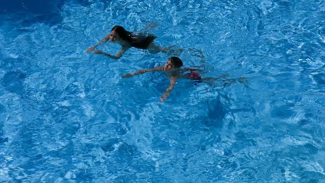 Two kids swim in pool together