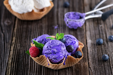 Obraz na płótnie Canvas Blueberry ice cream with bowl waffer and berries on wooden background
