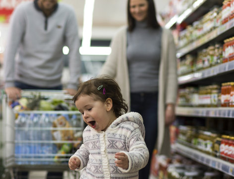 A cute little girl has fun shopping with her parents at the supermarket