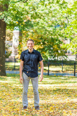 Obraz premium Manhattan New York City NYC Central park, young hipster millennial man standing, throwing many fallen leaves up in air in autumn fall season with yellow foliage