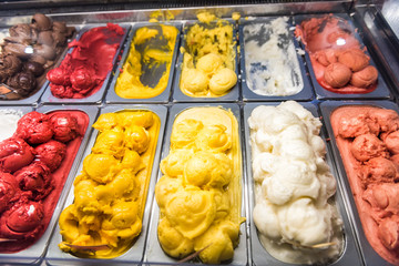 Ice cream frozen yogurt yellow red colorful serving counter parlour with many scoopable flavors, sorbet, chocolate, toppings