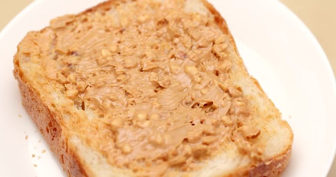 Applying peanut butter on white bread