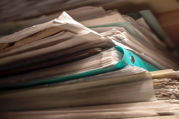 Paper documents in a mess. Chaos in business affairs. A pile of old papers is randomly on the shelf.