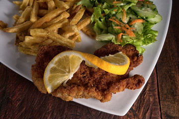 french fries, schnitzel and salad on plate