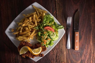 french fries, schnitzel and salad on plate