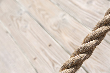 Obraz premium Aged rope with wooden floor boards in the background creating a natural aged texture for use as a background.