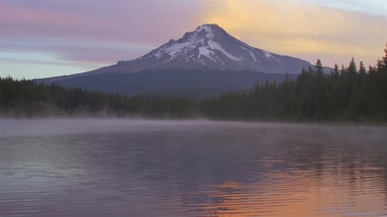 Scenic shot of a lake with morning fog, and a mountain in the background at sunrise - Powered by Adobe