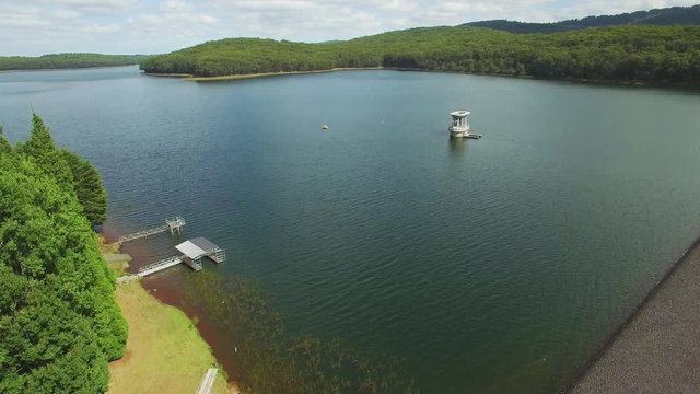 Slow rise over Silvan reservoir lake revealing beautiful forest and hills on bright sunny day