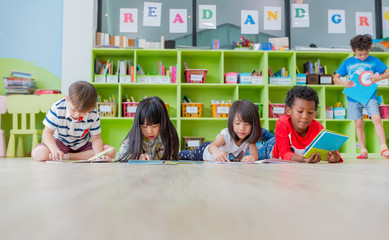 Group of diversity kid lay down on floor and reading tale book in preschool library,Kindergarten school education concept