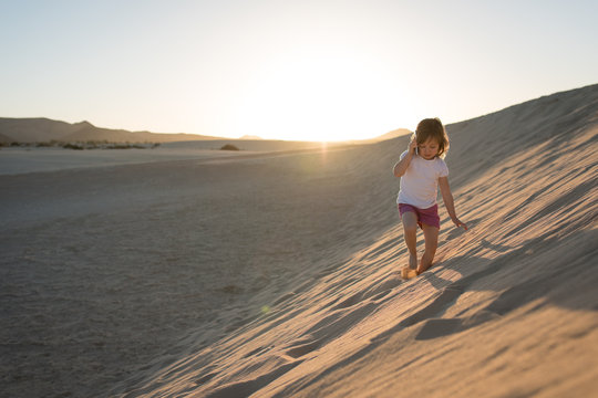 Little girl lost on sand dune at sunset and calling