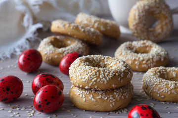 Traditional Greek Easter cookies with sesame seeds and colored eggs on the wooden table, selective focus, free space