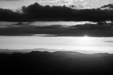 Sunset over mountains range in Umbria, with sun coming down behind some clouds