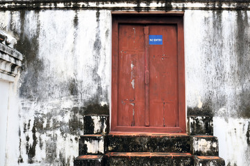 Ancient wooden door in castle wall archaeological site of thailand. No entry sign on the old door with grunge texture wall.