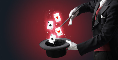 Magician making trick with wand and playing cards