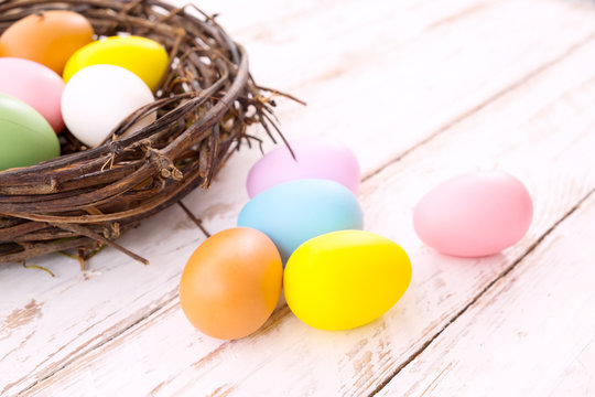 Colorful Easter eggs in nest on rustic wooden planks background. Holiday in spring season. vintage pastel color tone. Close up composition.