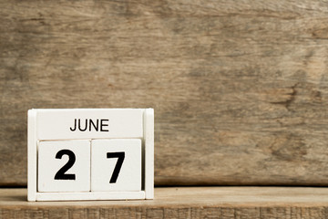 White block calendar present date 27 and month June on wood background