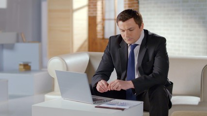 Serious businessman preparing company presentation on laptop, financial report