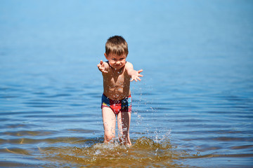 The boy splashes in the water of lake