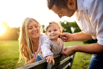 Happy family in a park in summer autumn. Mother, father and baby play in nature in the rays of...
