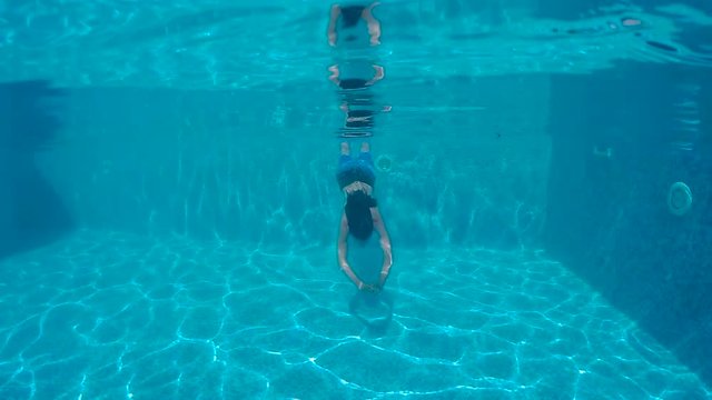 guy with beard and long hair dives into the pool with action camera