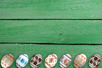 Happy Easter card. Colorful shiny easter eggs on green wooden table background. Copy space for text.